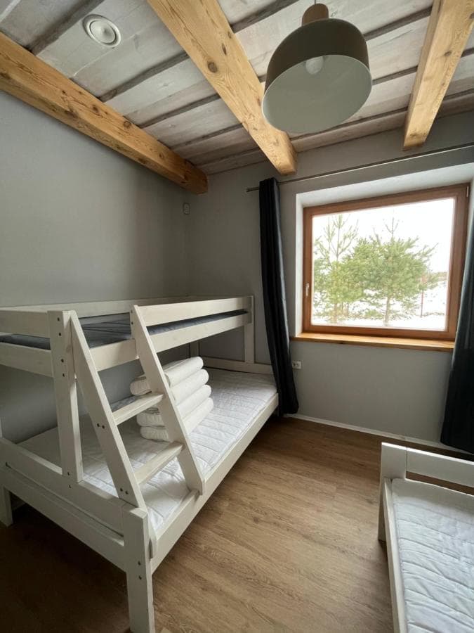 Miegamasis su dviaukštėmis lovomis, mediniais akcentais ir vaizdu į pušyną