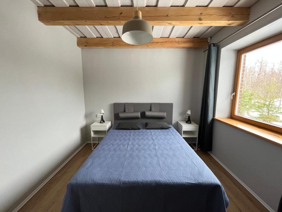 Ramus miegamasis su dvigule lova, medinėmis sijomis ir neutraliomis spalvomis