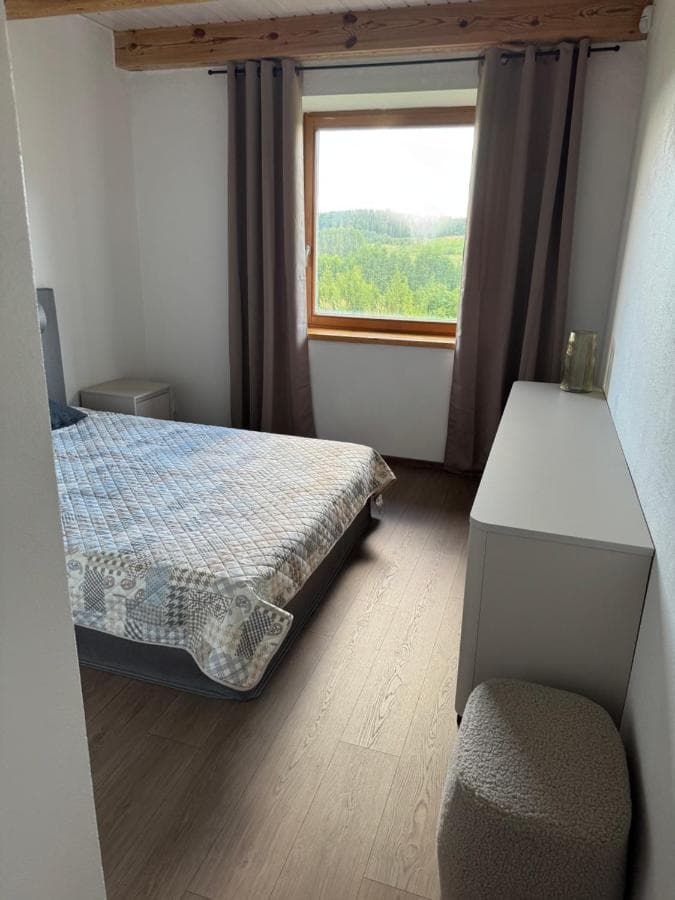 Ramus miegamasis su dvigule lova, medinėmis sijomis ir neutraliomis spalvomis